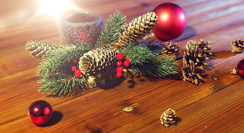 christmas, decoration, holidays and new year concept - close up of natural fir branch decoration with fir-cones, balls and candle in lantern on wooden table