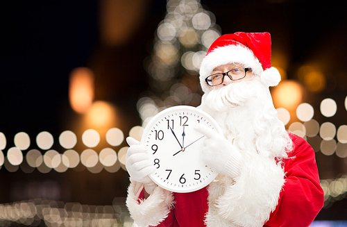 christmas time, holidays and people concept - santa claus with clock pointing finger to twelve