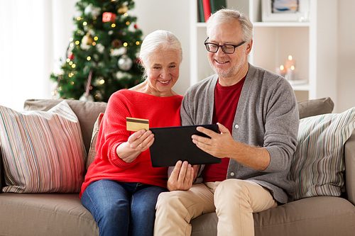 christmas, holidays and people concept - happy smiling senior couple with tablet pc computer and credit card shopping online at home