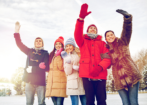 people, winter and friendship concept - happy friends waving hands in winter park