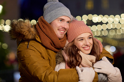 winter holidays and people concept - happy young couple dating and hugging in christmas evening outdoors