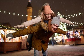 winter holidays and people concept - happy young couple dating and having fun at christmas market in evening