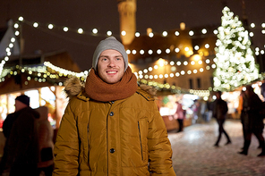 holidays and people concept - portrait of beautiful happy young man at christmas market in winter evening