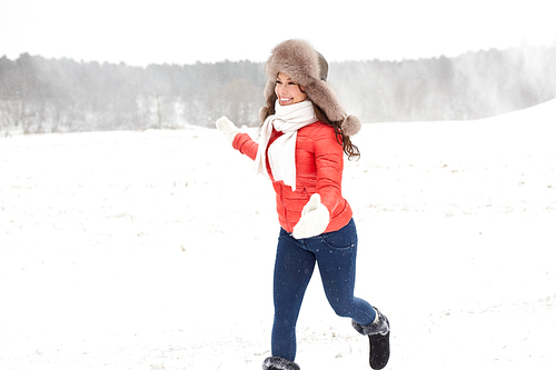 people, season and leisure concept - happy woman in winter fur hat having fun outdoors