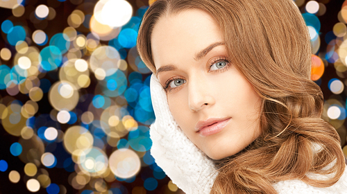 winter holidays, christmas and people concept - young woman in white gloves or mittens over lights background