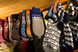 knitwear and winter clothes concept - woolen mittens at christmas market
