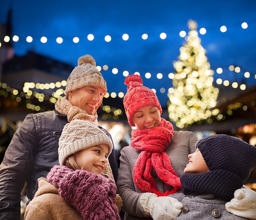 family, holidays and people concept - happy parents with kids outdoors over christmas tree lights background