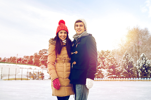 people, winter, friendship, love and leisure concept - happy couple ice skating on rink outdoors