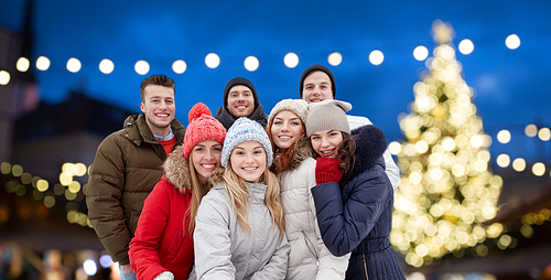 friendship, holidays and people concept - group of happy friends taking selfie outdoors over christmas lights background