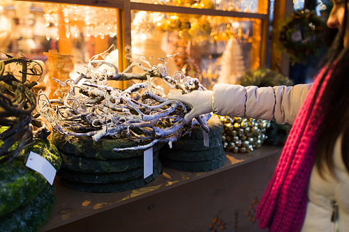 holidays and decoration concept - close up of woman with branch wreath at christmas market stall