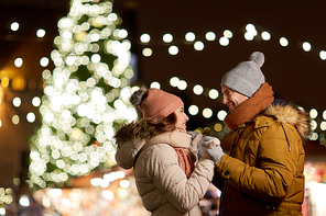 winter holidays and people concept - happy young couple dating at christmas tree in evening
