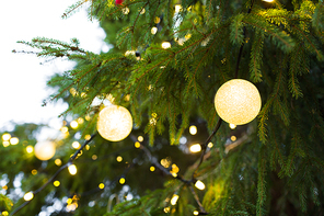 holidays and decoration concept - close up of christmas tree garland bulbs outdoors