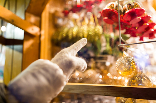 holidays and decoration concept - close up of hand pointing at christmas toys behind shop window