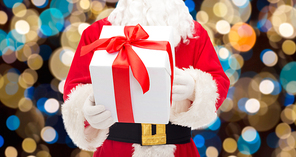christmas, holidays and people concept - close up of santa claus with gift box over lights background