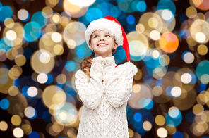 christmas, holidays and people concept - dreaming girl in santa helper hat over lights background