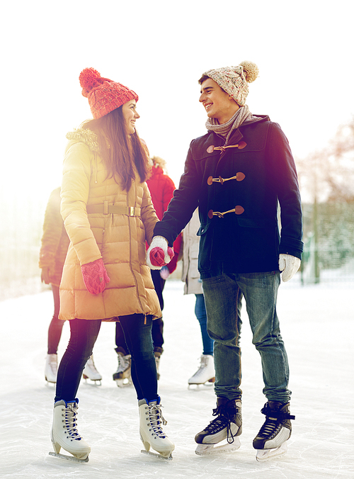 people, winter, friendship, sport and leisure concept - happy friends ice skating on rink outdoors