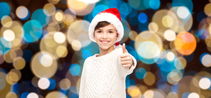 holidays, gesture, childhood and people concept - smiling happy boy in santa hat showing thumbs up over christmas lights background