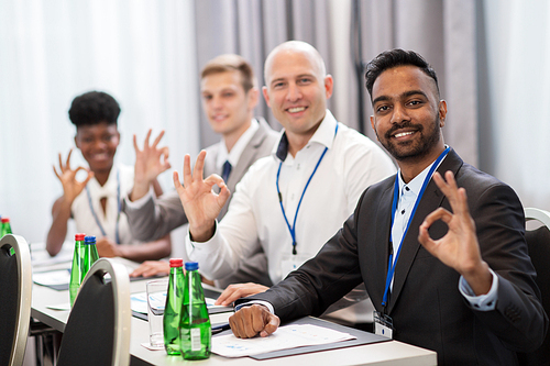 business, gesture and education concept - group of happy people at international conference showing ok hand sign