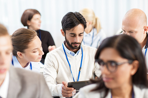 business and education concept - group of people with tablet pc computer at international conference