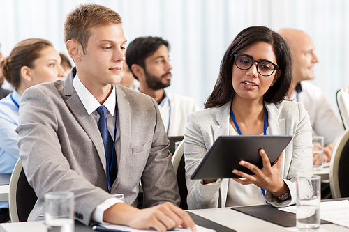 business, people and education concept - businessman and businesswoman with tablet pc computer at international conference