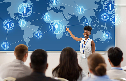 business, global network and people concept - smiling african american businesswoman or lecturer with world map on projection screen to group of students at conference presentation or lecture
