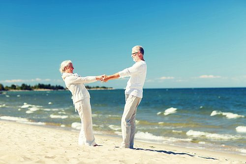family, age, travel, tourism and people concept - happy senior couple holding hands and dancing on summer beach