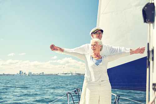 sailing, age, tourism, travel and people concept - happy senior couple enjoying freedom on sail boat or yacht deck floating in sea