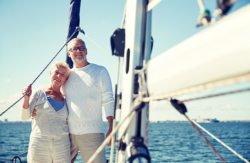 sailing, age, tourism, travel and people concept - happy senior couple hugging on sail boat or yacht deck floating in sea