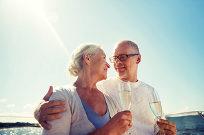 sailing, age, tourism, travel and people concept - happy senior couple drinking champagne on sail boat or yacht deck floating in sea