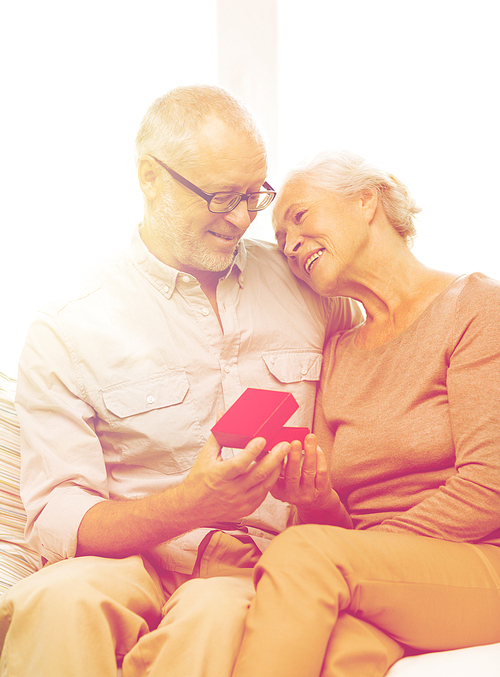 family, holidays, age and people concept - happy senior couple with little red gift box at home