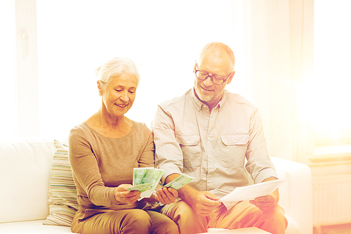 family, business, savings, age and people concept - smiling senior couple with papers, money and calculator at home