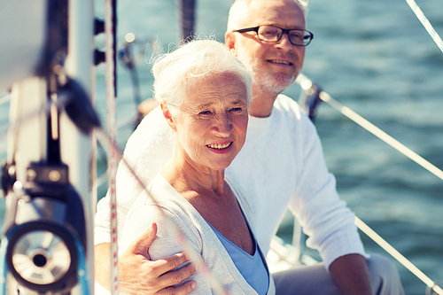 sailing, age, tourism, travel and people concept - happy senior couple hugging on sail boat or yacht deck floating in sea