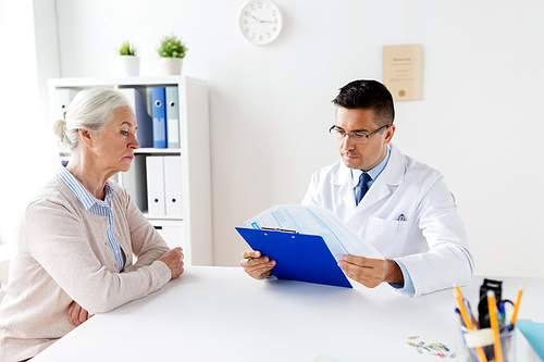 medicine, age, healthcare and people concept - senior woman and doctor with clipboard meeting at hospital