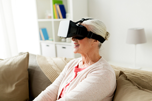 technology, augmented reality, entertainment and people concept - senior woman with virtual headset or 3d glasses playing videogame at home