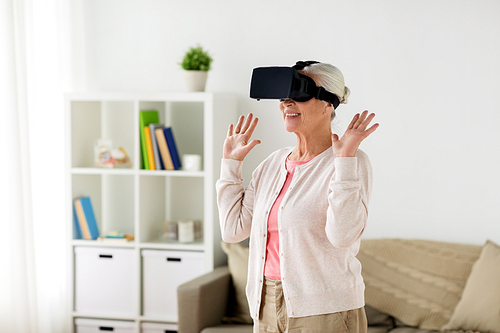 technology, augmented reality, entertainment and people concept - senior woman with virtual headset or 3d glasses playing videogame at home