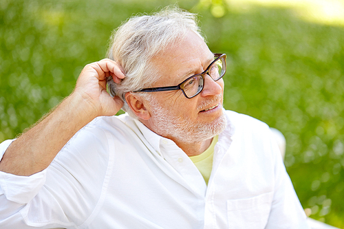 old age, retirement and people concept - happy senior man in glasses sitting at summer park