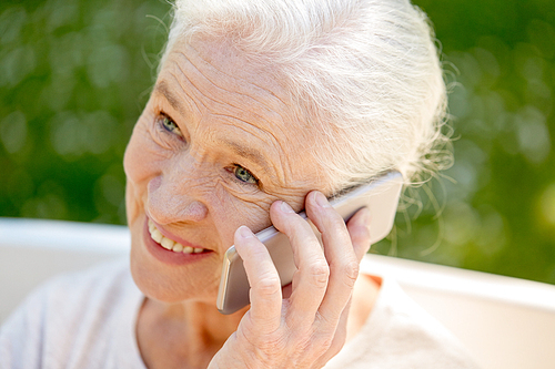 retirement, communication and old people concept - close up of happy senior woman calling on smartphone in summer