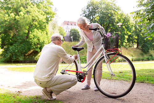 active old age, people and lifestyle concept - happy senior couple with fixie bicycle at summer city park