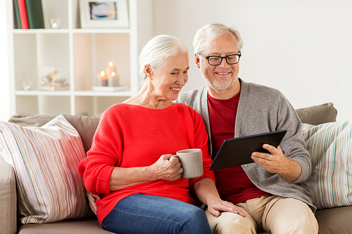 christmas, holidays and people concept - happy senior couple with tablet pc computer at home