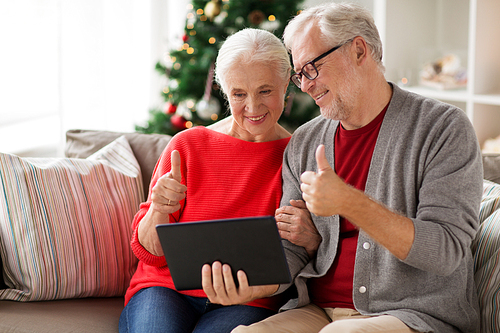 christmas, holidays, communication and people concept - happy smiling senior couple with tablet pc computer having video chat at home