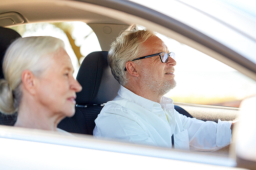 road trip, travel and old people concept - happy senior couple driving in car