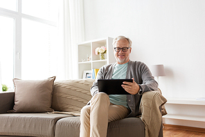 technology, old age, people and lifestyle concept - happy smiling senior man with tablet pc computer sitting on sofa at home