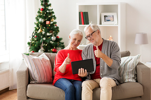 christmas, holidays, communication and people concept - happy smiling senior couple with tablet pc computer having video chat at home