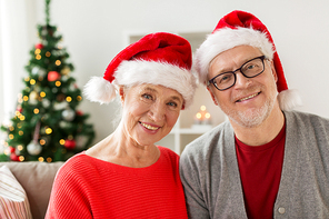 christmas, holidays and people concept - happy smiling senior couple in santa hats at home