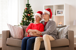 christmas, holidays and people concept - happy smiling senior couple in santa hats at home