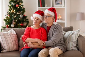 christmas, holidays and people concept - happy smiling senior couple in santa hats at home