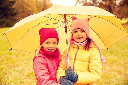 childhood, friendship, season, weather and people concept - happy little girls with umbrella in autumn park