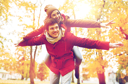 love, relationships, season and people concept - happy young couple having fun in autumn park