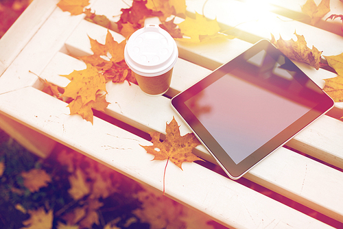 season, technology and advertisement concept - tablet pc computer and coffee paper cup on bench in autumn park