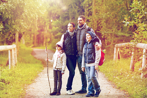 travel, tourism and hike concept - happy family walking with backpacks in woods